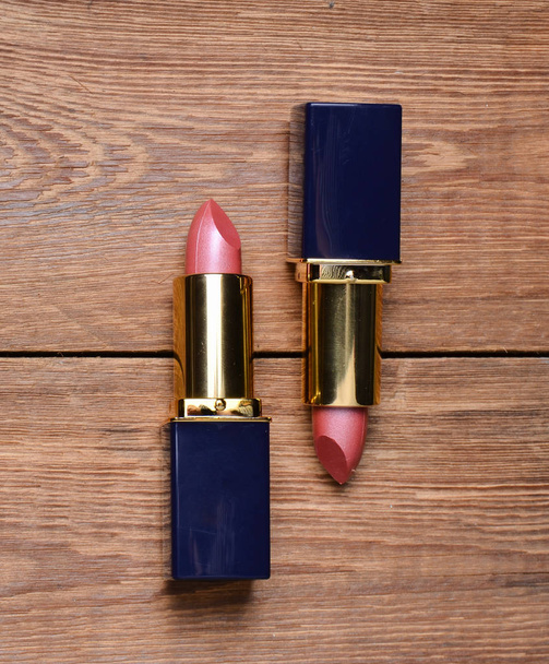 Two pink lipsticks on a wooden table. Top view - Fotografie, Obrázek