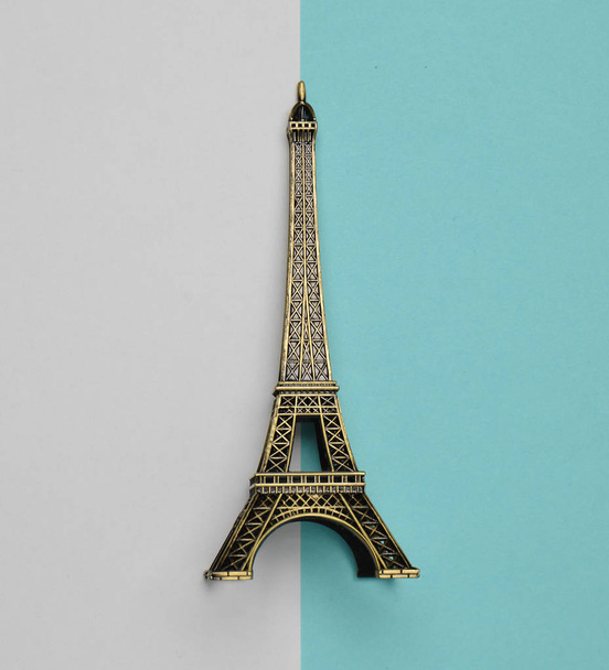 A souvenir statuette of the Eiffel Tower on a white blue pastel background. Top view. Minimalist trend - Photo, Image