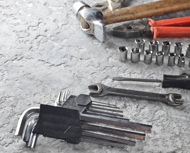 Working tool on a gray concrete background. Wrenches, hammer, screwdriver, pliers. Top view, copy space - Photo, Image