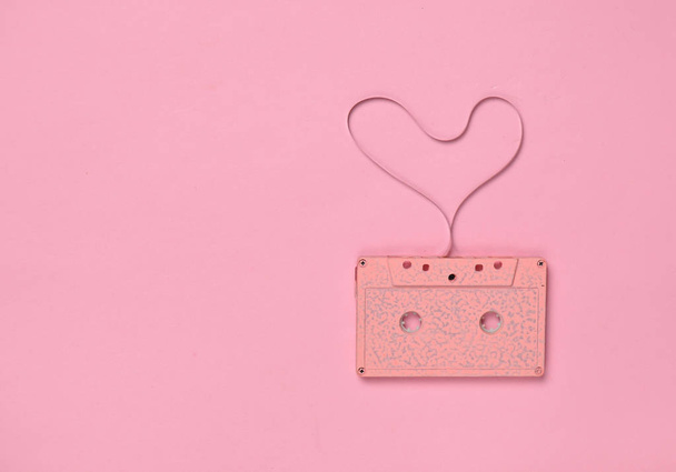 Heart shape from audio cassette tape on pink paper background, top view. Hipster Love - Φωτογραφία, εικόνα