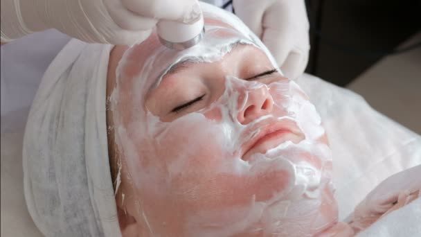 Ponto de massagem no rosto de uma menina gorda com a ajuda de um punho de um aparelho elétrico médico. O procedimento de levantamento ultra-sônico da pele facial
. - Filmagem, Vídeo