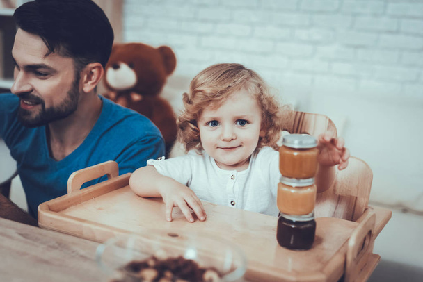 Baby with Bright Hair. Child on Chair. Jam. Smile. Spends Time. Happy Together. Leisure Time. Smiling Kids. Father. Having Breakfast. Man. Home Time. Sweet Baby. Enjoy. Childhood. Boy. - Photo, Image