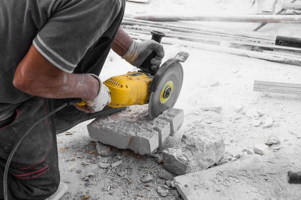 Worker cutting limestone block with power tool saw - 写真・画像