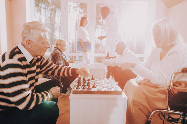 Senior Man and Woman. Play Chess. Nursing Home. Black. Doctor. Asian. Nurse. Stand Nearby. Rehabilitation. Elderly. Male. Patient. Patient on a Wheelchair. Sitting Woman. Young and Old People. - Fotó, kép