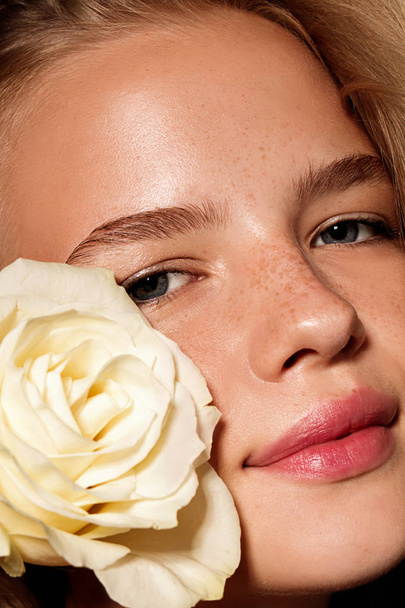Beauty young model with white rose. Perfect glow skin. Blonde hair. Fresh look. - Foto, Imagem