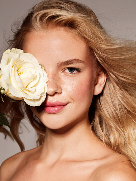 Beauty young model with white rose. Perfect glow skin. Blonde hair. Fresh look. - Photo, image