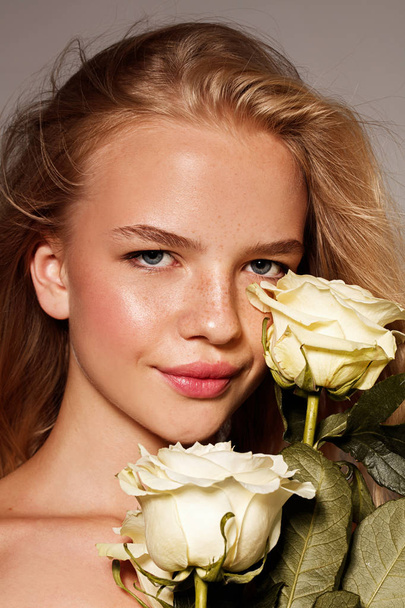 Beauty young model with white rose. Perfect glow skin. Blonde hair. Fresh look. - Zdjęcie, obraz