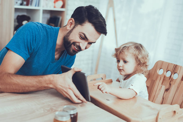 Tablet. Child on Chair. Jam. Smile. Happy Together. Spends Time. Leisure Time. Oranges. Smiling Kids. Father. Flakes with Milk. Delisious Food. Father Two Boys. Having Breakfast. Man. Home Time. - Foto, imagen