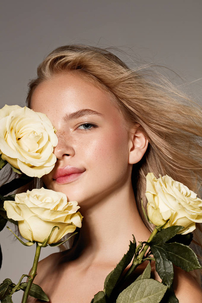 Beauty young model with white rose. Perfect glow skin. Blonde hair. Fresh look. - Foto, afbeelding