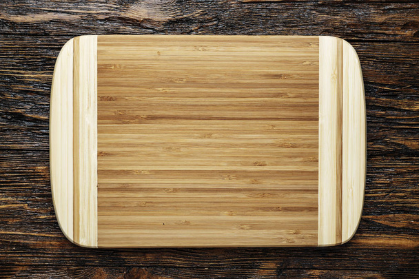 A cutting wooden board rests on a wooden background. place for text or for a recip - Foto, Bild