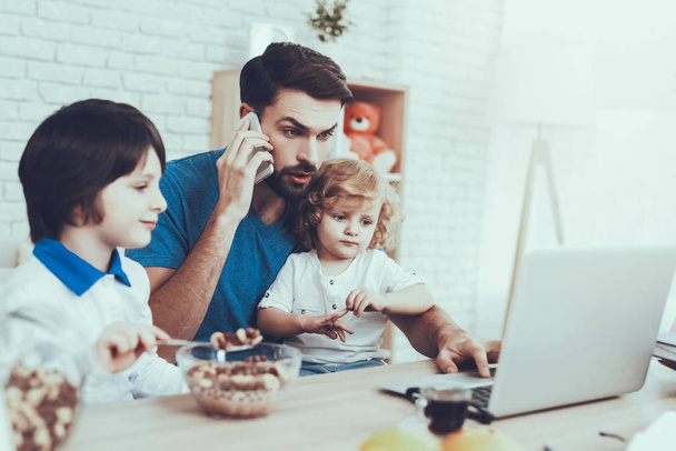 Having Breakfast. Father. Works at Home. Upbringing. Looks After Children. Spends Time. Happy Together. Leisure Time. Smiling Kids. Father Two Boys. Man. Home Time. Baby with Bright Hair. Laptop. - Foto, imagen