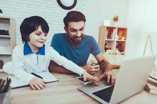Father Two Boys. Homework. Upbringing. Looks After Children. Spends Time. Happy Together. Leisure Time. Smiling Kids. Father. Man. Home Time. Baby with Bright Hair. Works at Home. Laptop. - 写真・画像