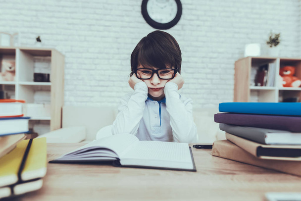 Intelligent. Glasses. Boy. Pensive Look. Exhausted. Sit at Homework. Sit at the Table. Textbook. Exercise Book. Study. Tired Kid. Notebook. Difficulties Tasks. Household. Domestic Life. Teddy Bear. - 写真・画像