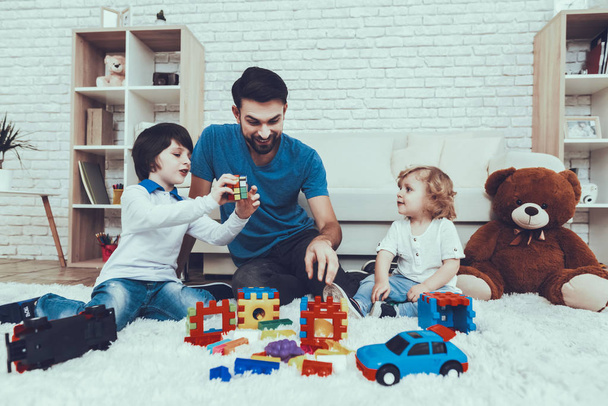 Spends Time. Happy Together. Leisure Time. Smiling Kids. Father. Father Two Boys. Man. Smile. Home Time. Baby with Bright Hair. Two Boys. Plays Games. Toys. Teddy Bear. Cars. Holidays. - Fotografie, Obrázek