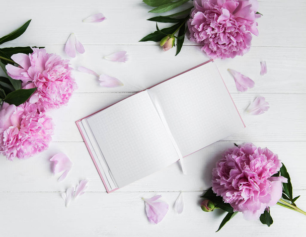note book with peonies on a white wooden background - Foto, imagen