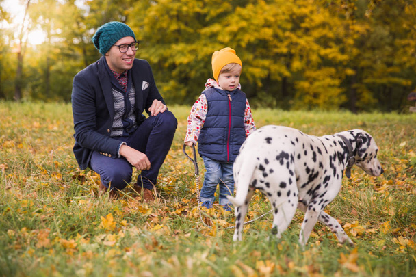 The little cute boy with young happy father walking on nature with their friend dalmatian dog - Fotoğraf, Görsel