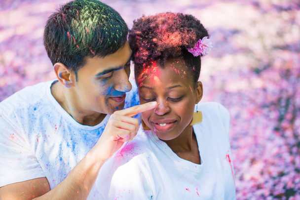 Portrait of the young happy couple who painting with paint face of each other outdoors - Photo, image