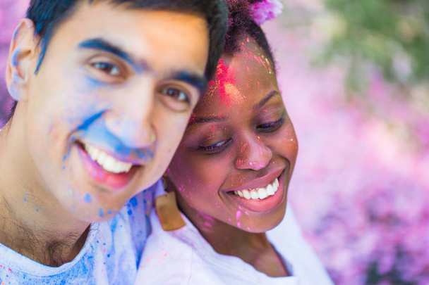Portrait of the young happy couple with paint on their faces outdoors - Foto, afbeelding