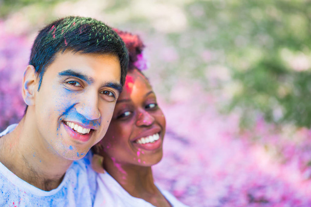 Portrait of the young smiling couple with paint on their faces outdoors - Foto, Imagem