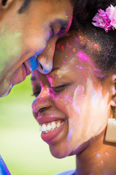 Close-up the young couple in love with paints on their faces standing face to face and smiling outdoors - 写真・画像