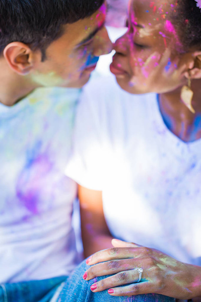 Portrait of the young couple in love with paints on their faces who sitting face to face outdoors - Foto, immagini
