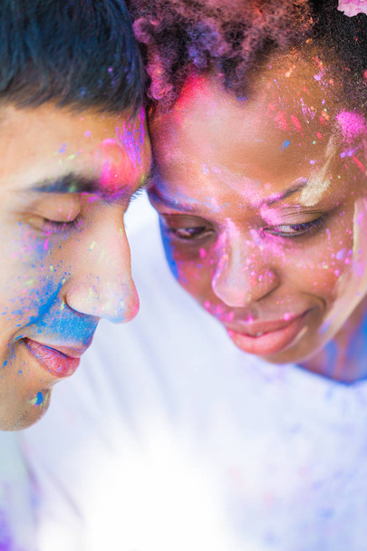 Close-up the young couple in love with paints on their faces sitting face to face outdoor and smiling - Fotografie, Obrázek