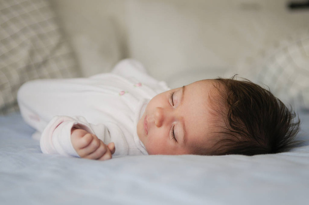Newborn baby girl sleeping on blue sheets at home - Φωτογραφία, εικόνα