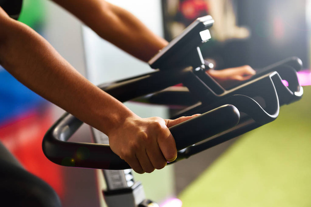Primer plano del entrenamiento de las manos de la mujer en un gimnasio haciendo spinning o cyclo indoor. Concepto de deporte y fitness
. - Foto, imagen