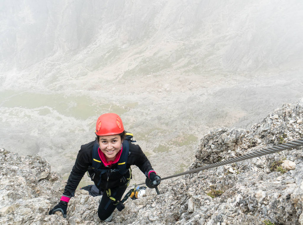 jovem alpinista feminina atraente em uma íngreme e exposta Via Ferrata em Alta Badia, no Tirol do Sul, nas Dolomitas italianas
 - Foto, Imagem
