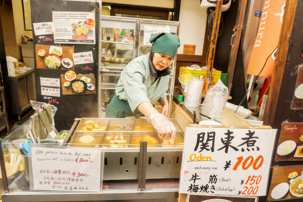 osaka, japan, 16. Februar 2018: japanische Händlerin und ihr japanischer Imbiss "o-den". Es ist ein Lebensmittel, das eine Vielzahl von Lebensmitteln (Fischbällchen, Ei, Rettich) kombiniert und im Winter gerne gegessen wird. - Foto, Bild