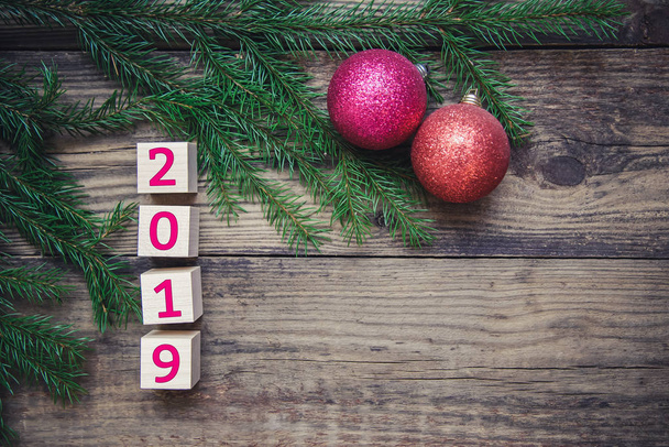 Prachtige kaart met Nieuwjaar 2019 en kerstboom takken met twee ballen op een houten rustieke achtergrond, met kopie ruimte, bovenaanzicht - Foto, afbeelding