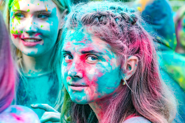 Jovens adolescentes enérgicos no festival de pinturas de holi na Rússia. A divertir-se ao ar livre. Pó multicolorido cores do rosto. Retrato de close-up
 - Foto, Imagem