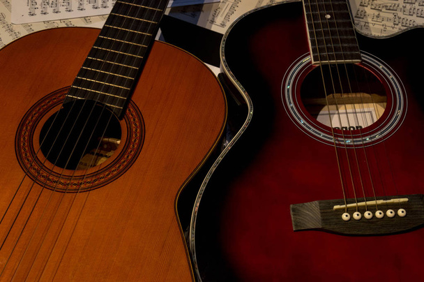 Twee gitaren een akoestische en een ander Spaans op een tabel met scoort. - Foto, afbeelding
