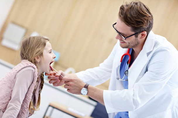 Klein meisje in kliniek met een checkup met laryngologist - Foto, afbeelding