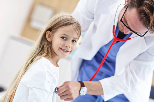 Little girl in clinic having a checkup with pediatrician - Фото, изображение