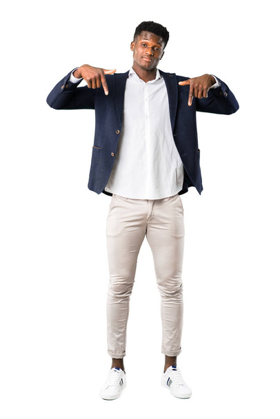 Cuerpo completo de hombre afroamericano guapo con una chaqueta apuntando hacia abajo con los dedos sobre fondo blanco
 - Foto, Imagen