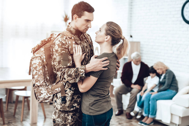 A Man Goes To Military Service. Saying Goodbye. Leaving To Army. Farewell With Family. Camouflage Uniform. Wife Hanging. Feelings Showing. Guard Of Peace. Patriotic Decision. Soldier Emotion. - Photo, image