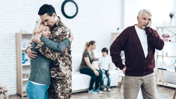 A Man Goes To Military Service. Saying Goodbye. Leaving To Army. Farewell With Family. Camouflage Uniform. Parent Hanging. Feelings Showing. Guard Of Peace. Patriotic Decision. Soldier Emotion. - Photo, image
