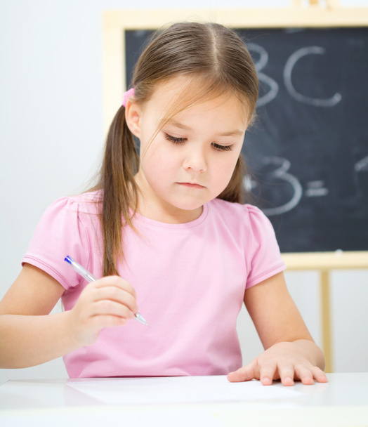 Little girl is writing using a pen - Foto, immagini