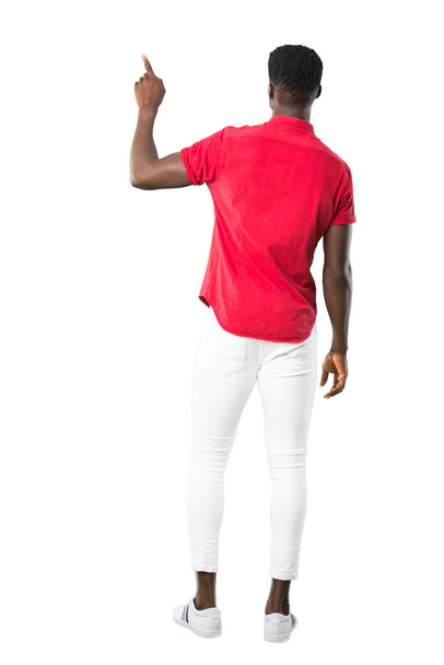 Full body of Young african american man pointing back with the index finger on white background - Fotó, kép
