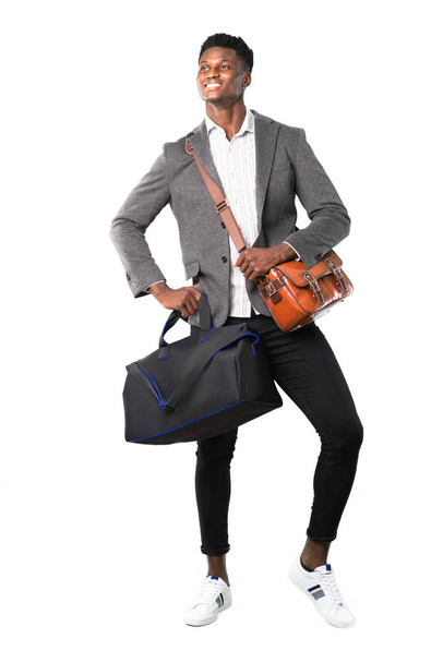 Ganzkörper eines afrikanisch-amerikanischen Geschäftsmannes, der mit Koffern reist und mit Armen an der Hüfte auf weißem Hintergrund posiert - Foto, Bild