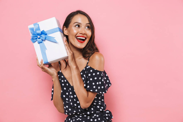 Photo of happy excited emotinal woman isolated over pink background holding susprise gift box. - Fotografie, Obrázek