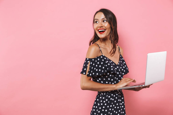 Photo of happy beautiful woman isolated over pink background using laptop computer typing. - Foto, immagini