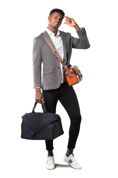 Full body of African american business man traveling with suitcases having doubts and with confuse face expression while scratching head on white background - Foto, afbeelding