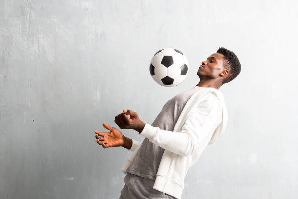 Deportista afroamericano sosteniendo una pelota de fútbol
 - Foto, imagen