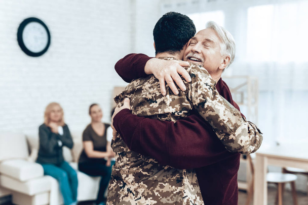 A Man Returns From The Military Service. Family Meeting. Leaving From War. Embrace With Family. Camouflage Uniform. Dad Hanging. Feelings Showing. Patriotic Comeback. Soldier Emotion. - Fotografie, Obrázek