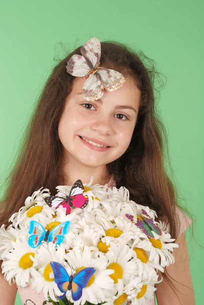 Portrait d'une jeune fille avec un bouquet de camomilles. Isolé sur fond vert
. - Photo, image