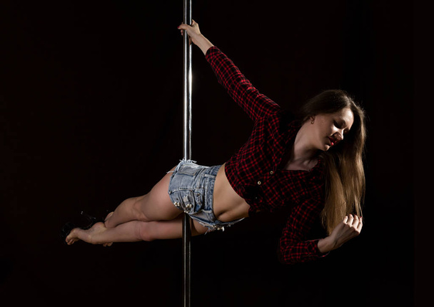 beautiful go-go dancer in denim shorts and checkered shirt in night club. Pole Dance pin-up girl - Фото, зображення