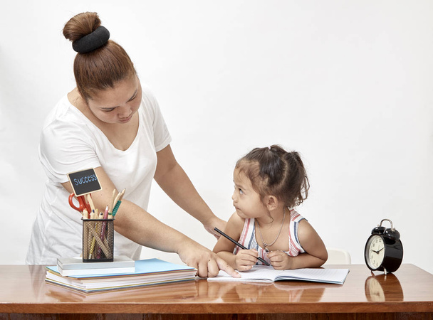 Пн і дитина дівчина тайці роблять домашнє завдання вдома. Простір для дизайну
 - Фото, зображення