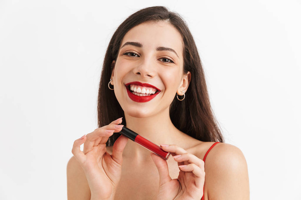 Photo of young happy excited woman posing isolated holding lip gloss doing makeup. - Photo, image